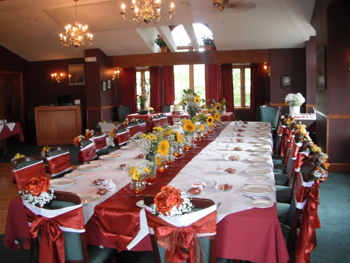 The showroom set for a banquet: one long table dressed in red and white under the chandeliers