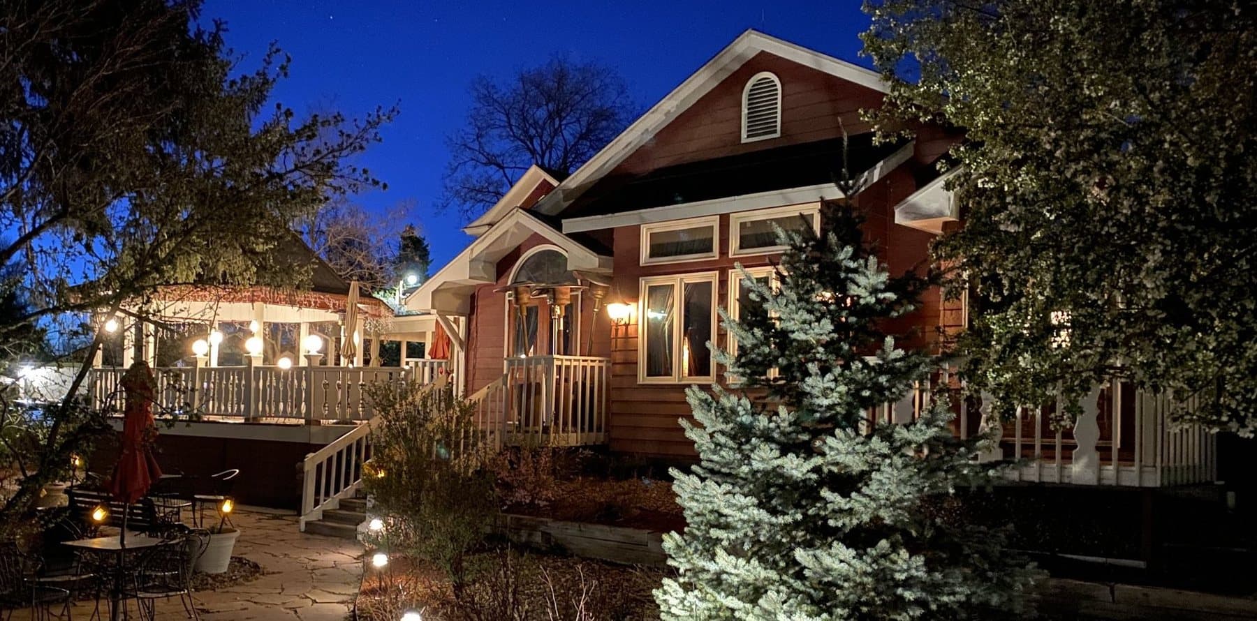 The Magic Manor at dusk: the Victorian house, its deck and gazebo lit against a deep blue sky