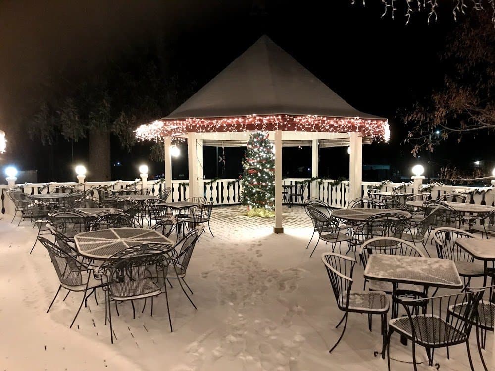 The patio and its gazebo on a snowy evening, strung with lights around a Christmas tree